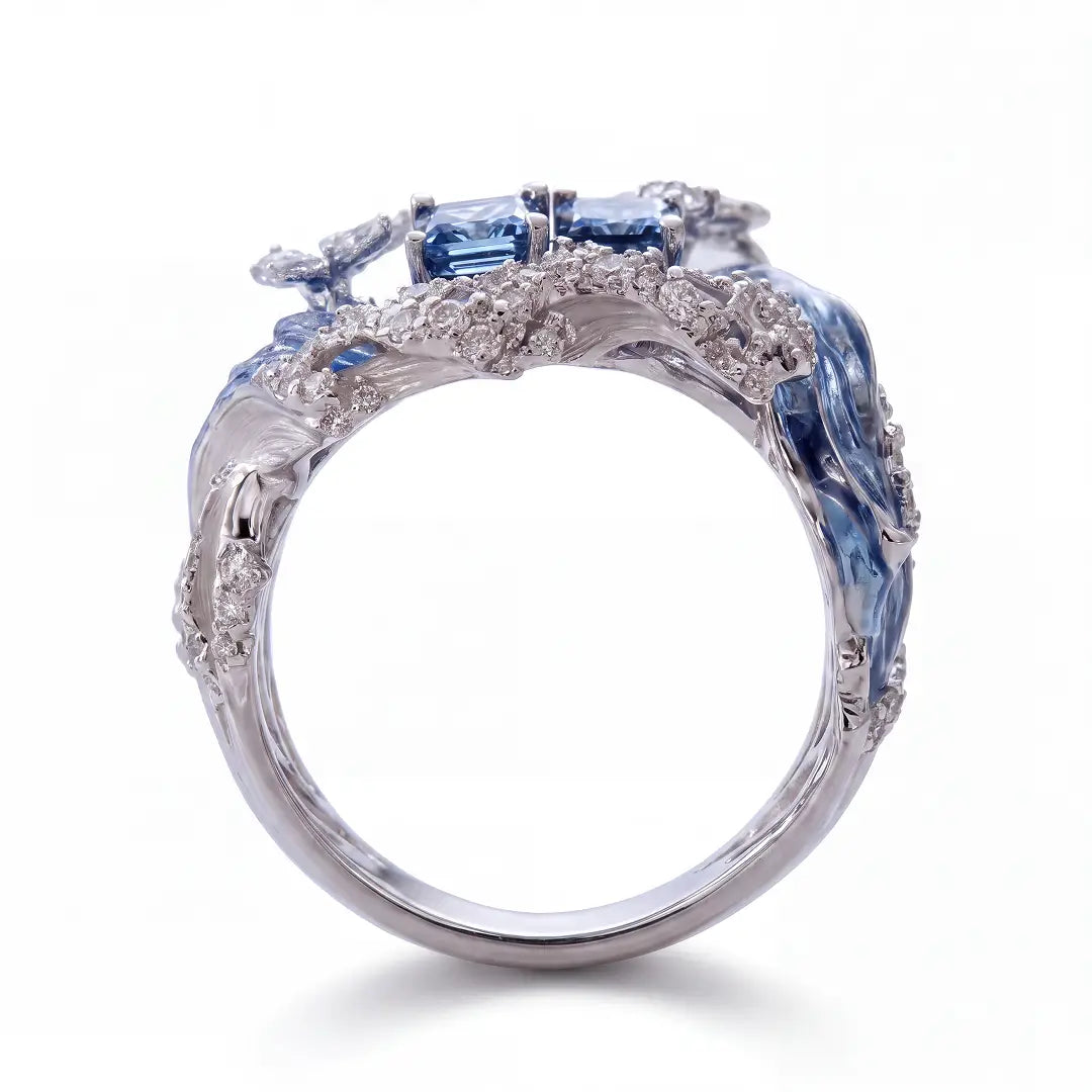 An ornate silver ring featuring blue gemstone accents and clear stones, shown on a clean white background.
