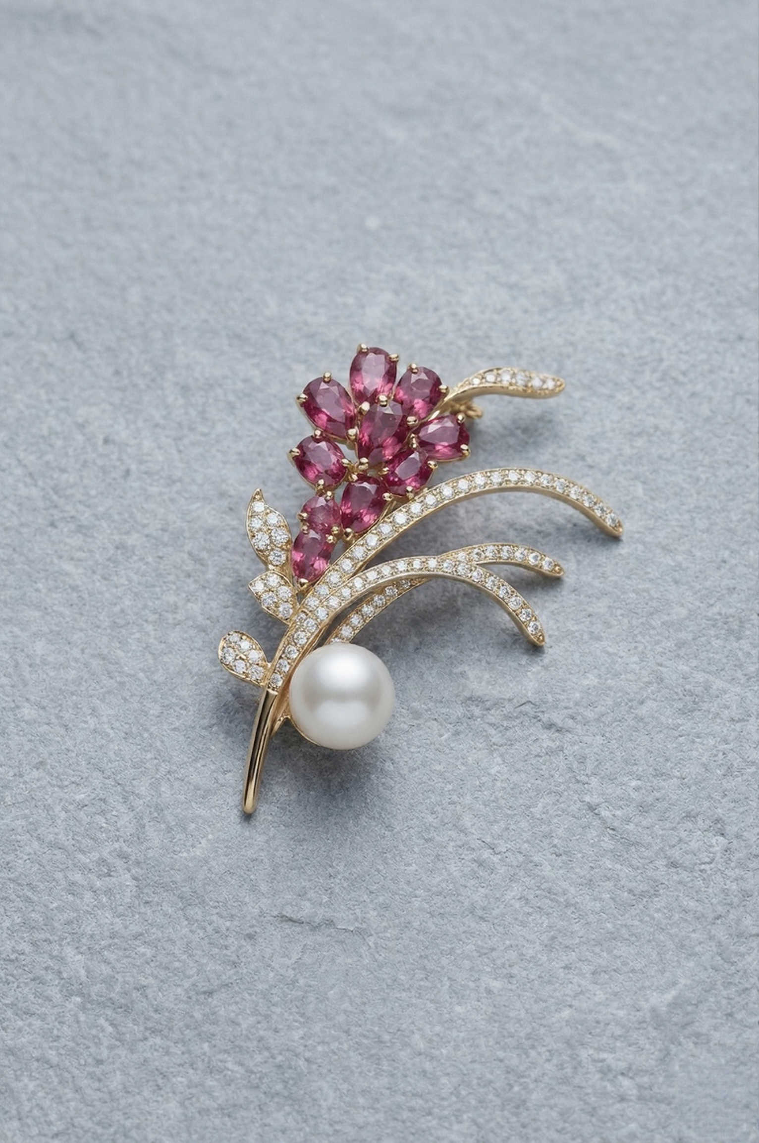 Jewelry brooch with pink gemstones and a pearl on a gray background