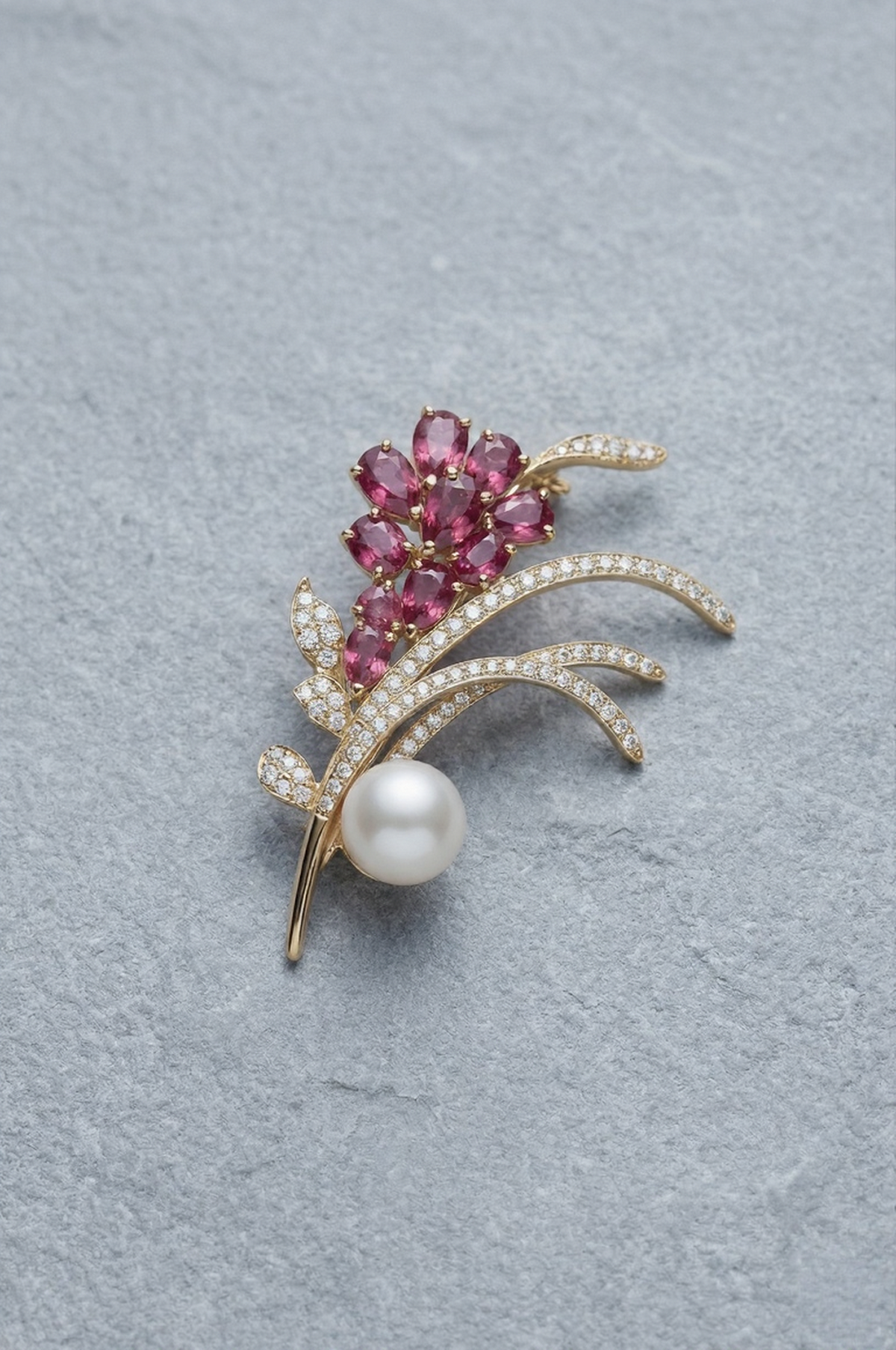 Jewelry brooch with pink gemstones and a pearl on a gray background