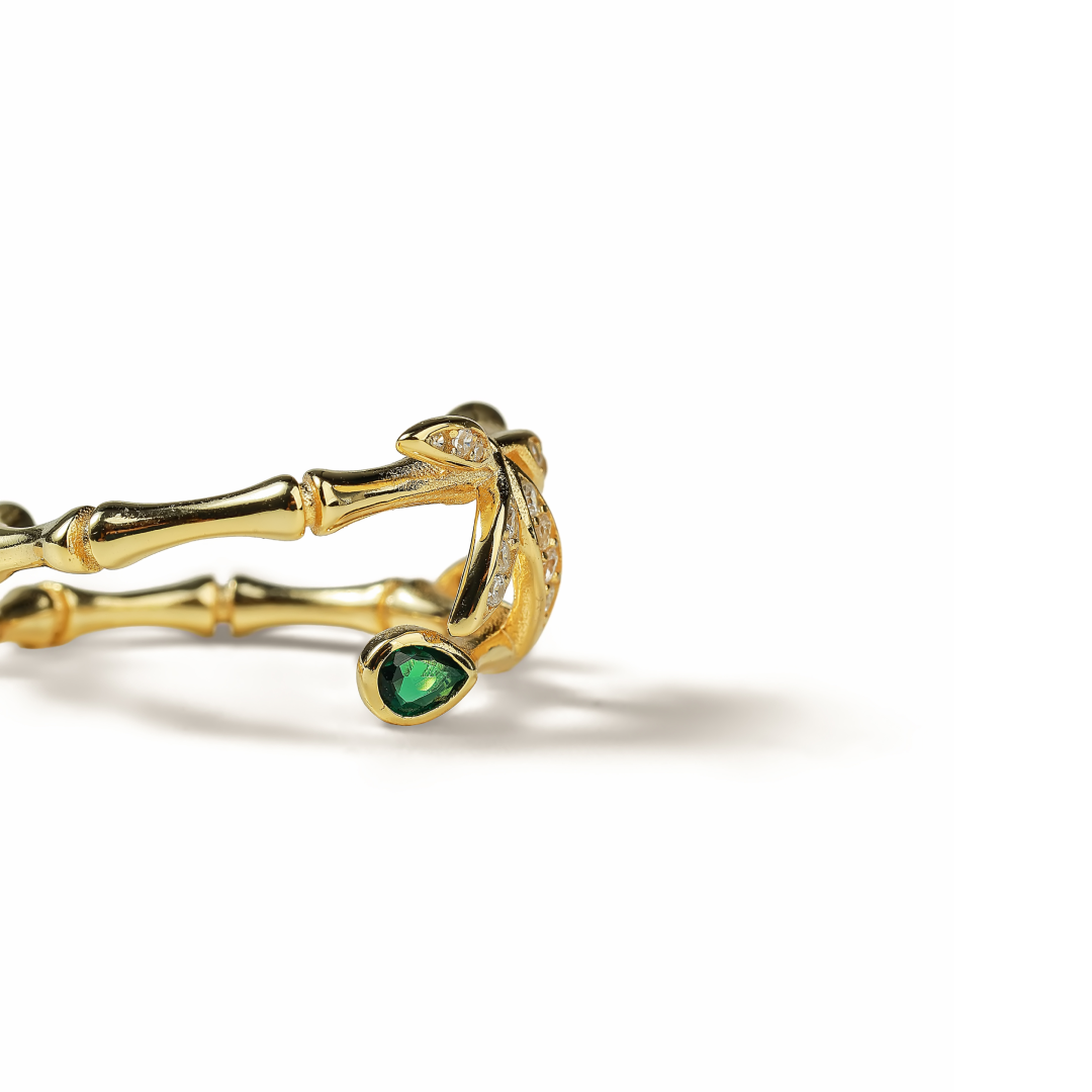 Aiko Tanaka ring part side view, a gold bamboo branch setting with a pear-shaped green stone, on a white background