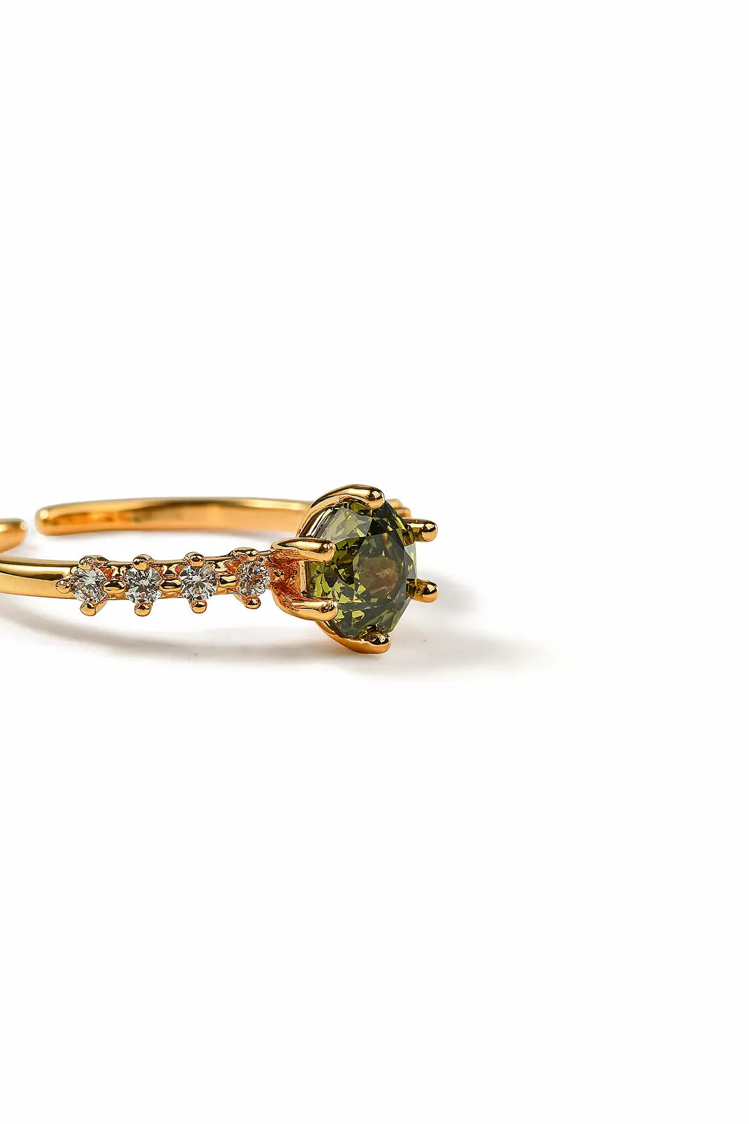 Aiko Tanaka Rensei ring side view, a gold band with a green center stone and crystal accents, white background